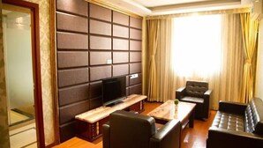 A modern living room with a flat-screen TV, leather sofas, a wooden coffee table, and a large window with curtains. - GreenTree Inn TianJin Ji County South YuYang Road GuLou Square Express Hotel (Tianjin)
