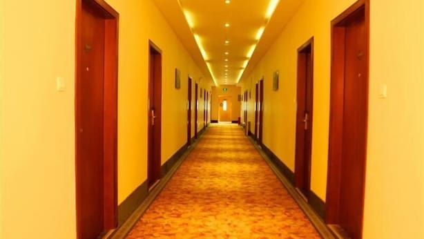A long, narrow hotel corridor with doors on both sides, carpeted floor, and overhead lighting. - GreenTree Inn Haikou Longhua District Guomao Hotel (Haikou)