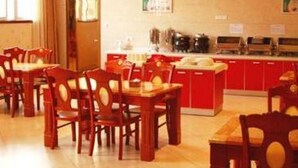 A dining area with wooden chairs and tables, a red counter with kitchen appliances, and a window with curtains.