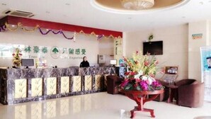 A hotel reception area with a marble counter, a large floral arrangement, and a ceiling with a circular light fixture.