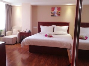 A hotel room with a large bed, a bedside table, a chair, and a painting on the wall. - GreenTree Inn Chuzhou Wandong International Car City Express Hotel (Chuzhou)