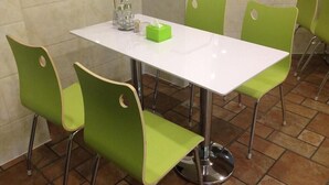 A dining area with a white table and four green chairs. - Vatica Lianyungang Zhongyin Mingdu Hotel (Lianyungang)