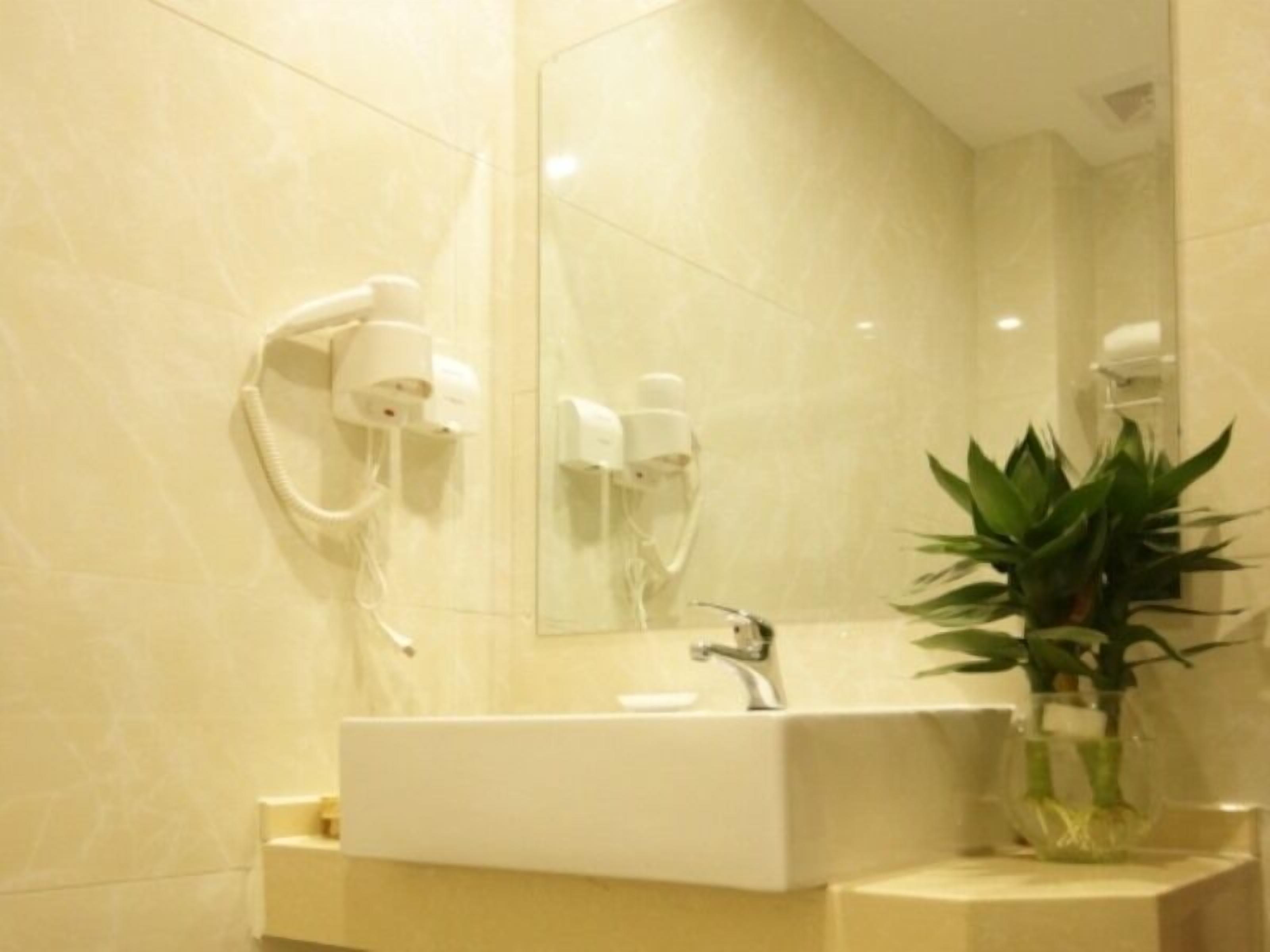 A modern bathroom with a large mirror, a sink, and a wall-mounted hairdryer.