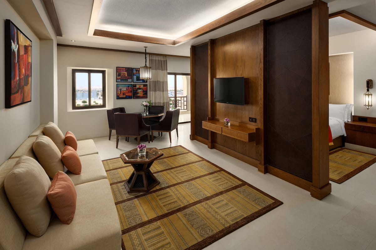 A modern living room with a sofa, a coffee table, a TV, and a dining area with chairs and a table.