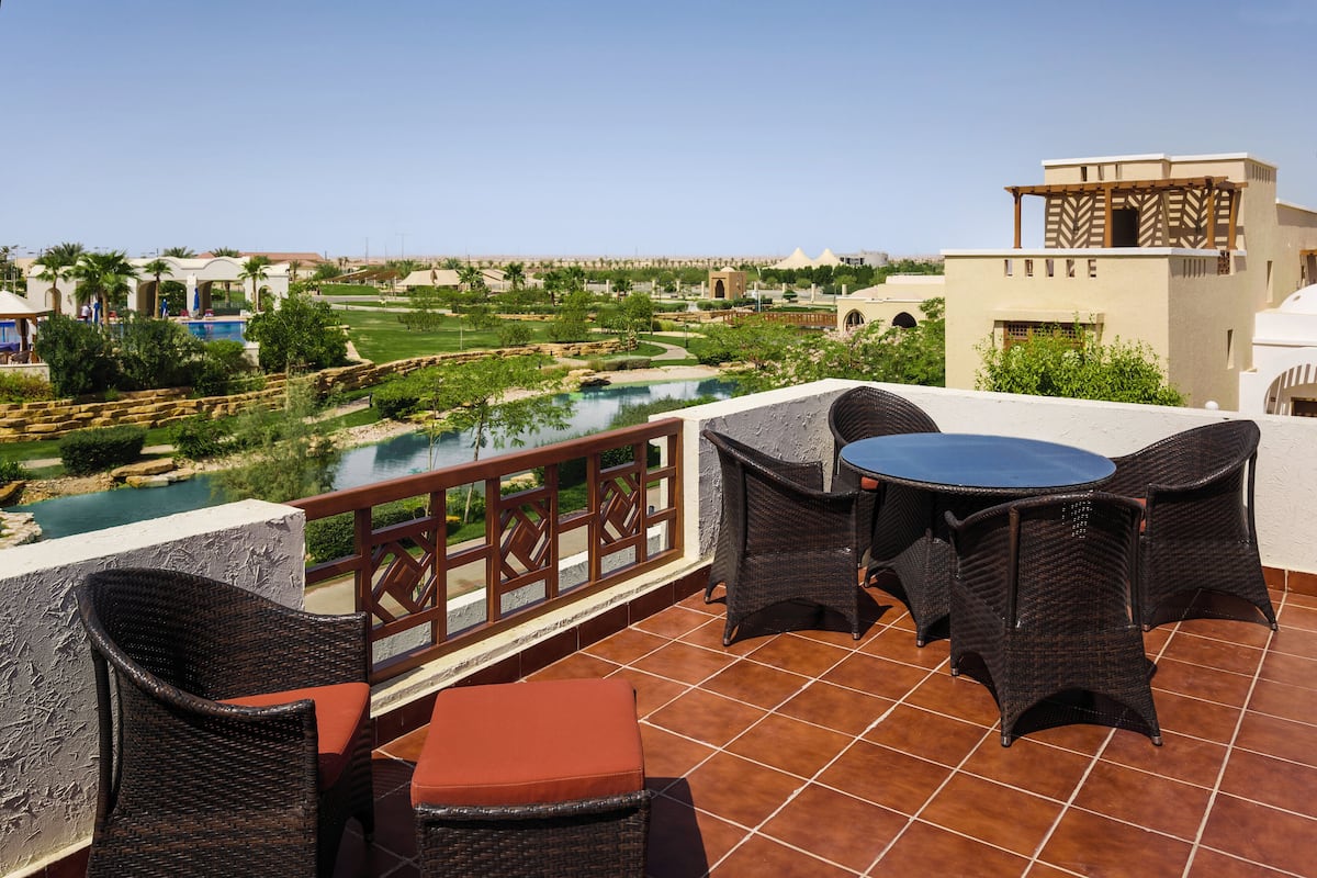 A terrace with wicker furniture, a pool, and a view of a golf course.