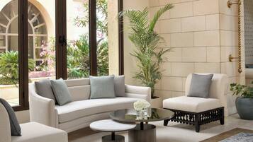 A modern living room with a white sofa, two armchairs, a coffee table, and a large window with a view of greenery.