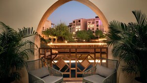A balcony with wicker chairs, a wooden railing, and a view of buildings in the background. - InterContinental Durrat Al Riyadh Resort & Spa by IHG (Riyadh)
