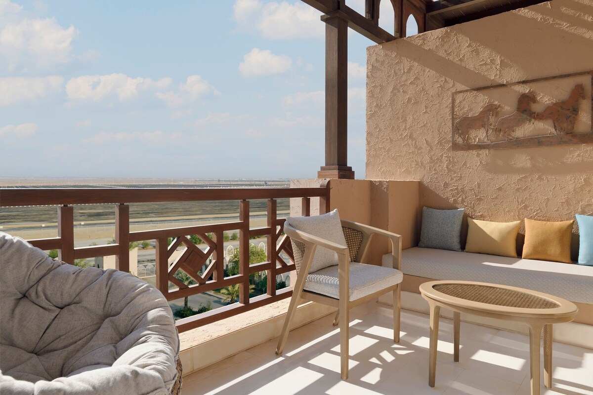 A balcony with wicker furniture, a cushioned sofa, and a painting on the wall.