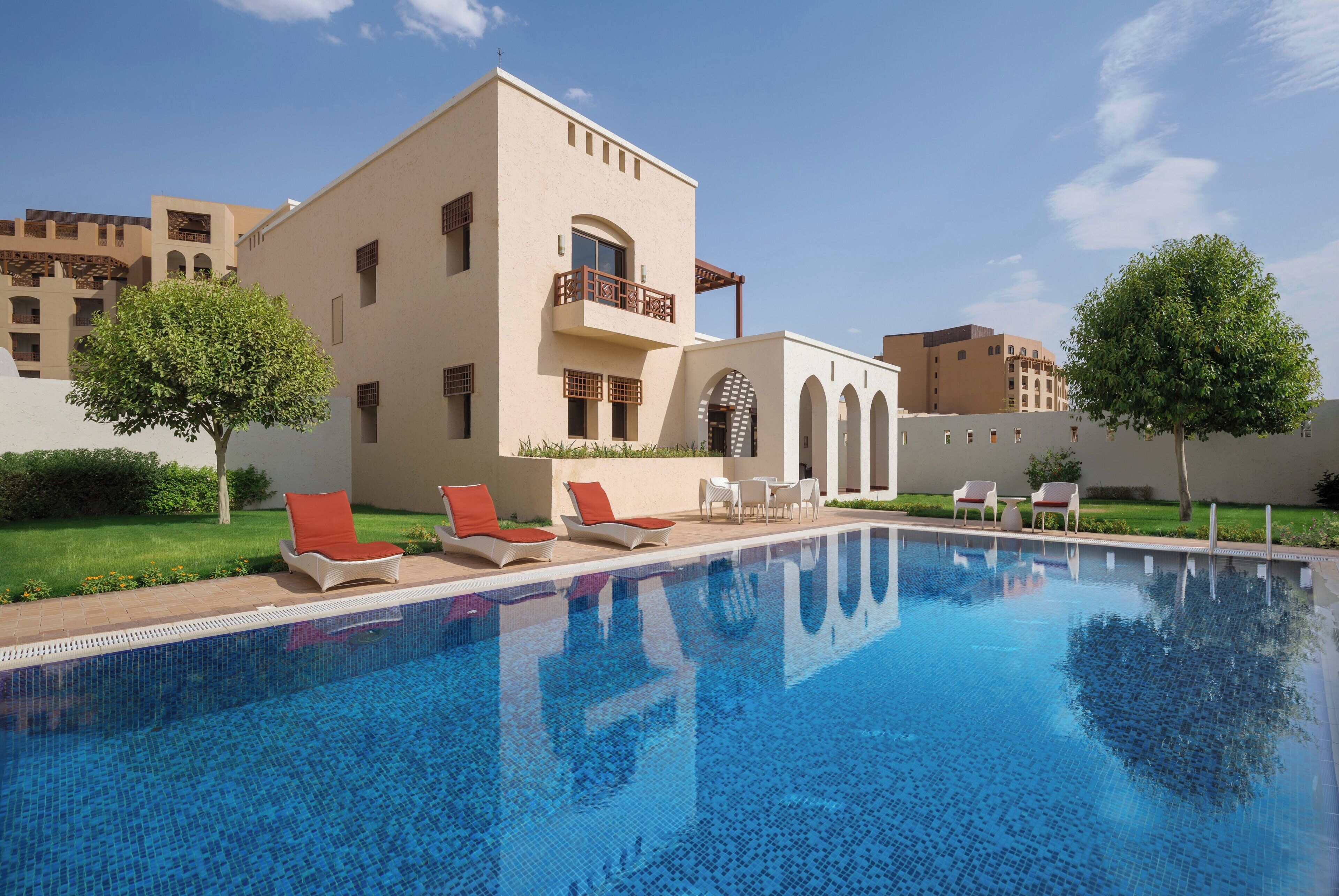 A swimming pool with lounge chairs and a building with balconies.