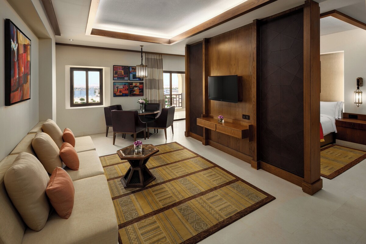 A modern living room with a sofa, a coffee table, a TV, and a dining area with chairs and a table.