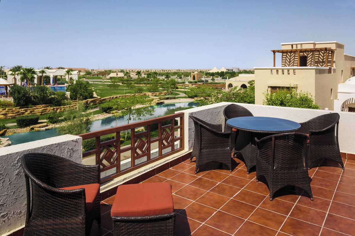 A terrace with wicker furniture, a pool, and a view of a golf course.