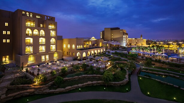 A hotel with multiple floors, outdoor seating areas, and a landscaped garden with a pool. - InterContinental Durrat Al Riyadh Resort & Spa by IHG (Riyadh)