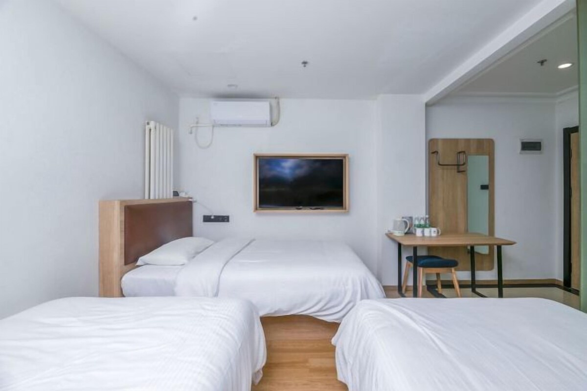 Ein modernes Hotelzimmer mit zwei Einzelbetten, einem Schreibtisch und einem Stuhl.