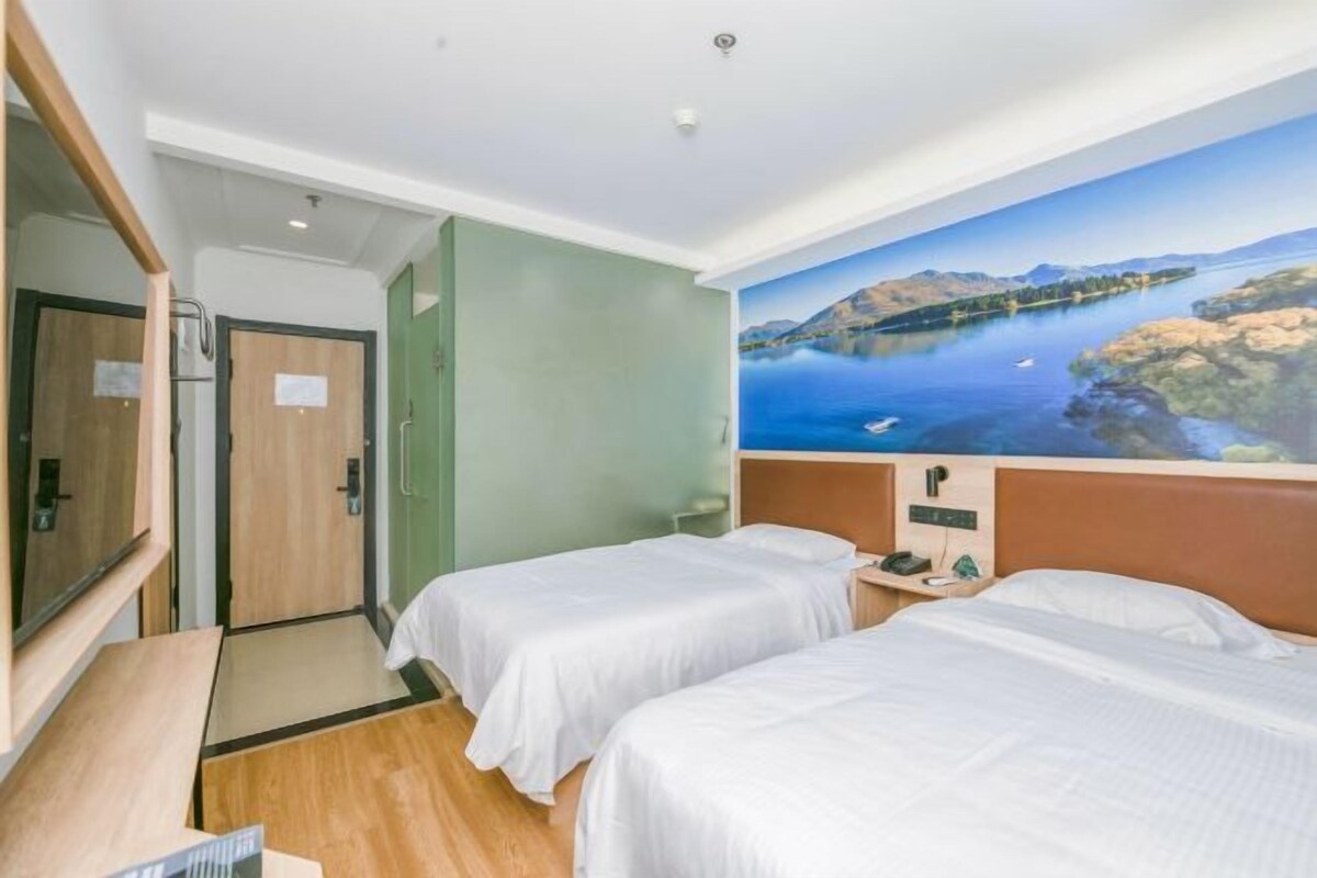 Ein Hotelzimmer mit zwei Betten, einem Holztisch, einem Spiegel und Blick auf einen malerischen See.