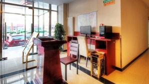 Un espace d’accueil avec un bureau, un ordinateur et une carte affichée au mur.