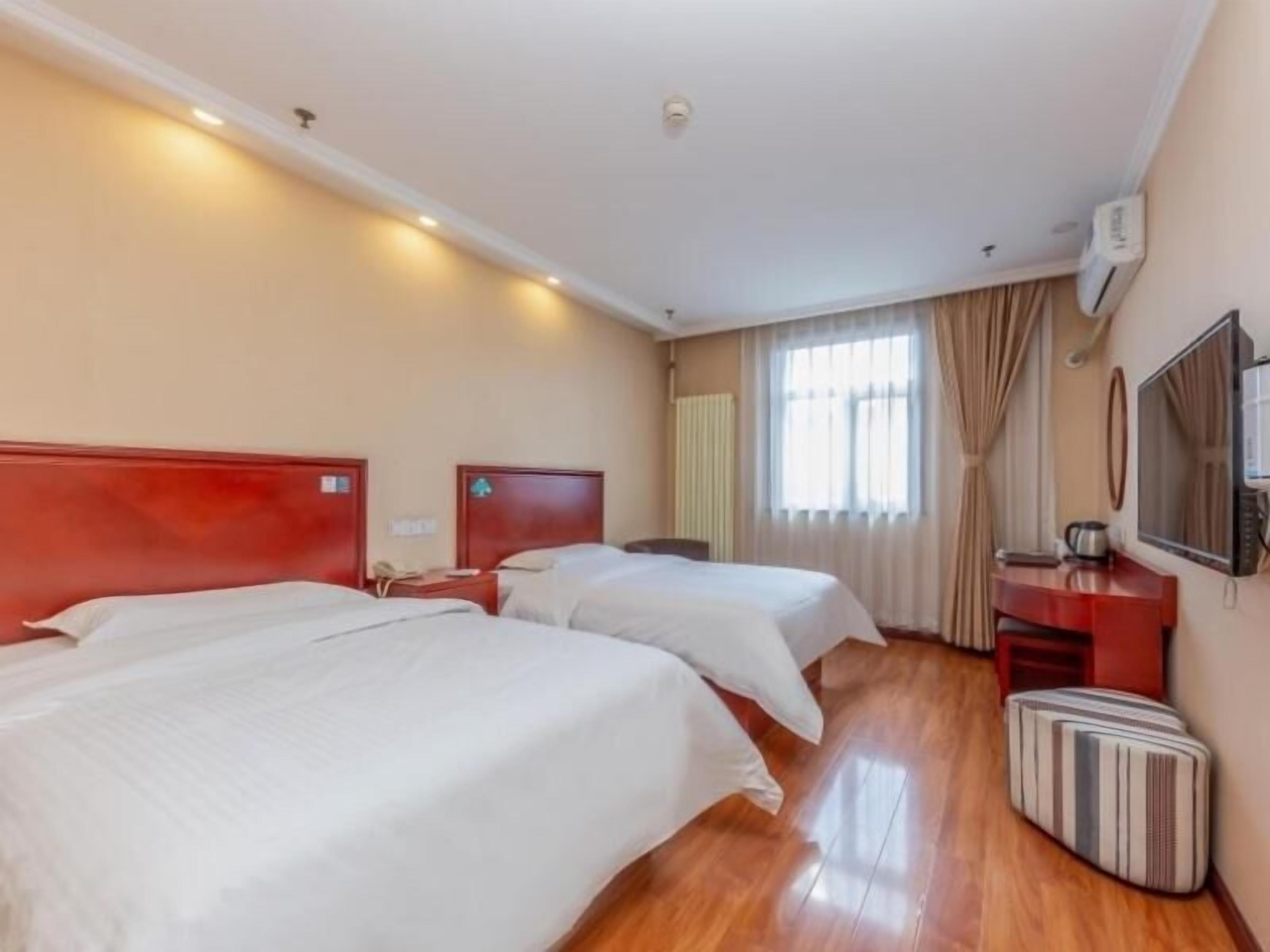A hotel room with two beds, a TV, a desk, and a suitcase.