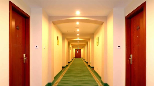 A hotel hallway with a green carpet, wooden doors, and a light-colored ceiling. - Greentree Inn Beijing Yanqing Railway Station (Yanqing)