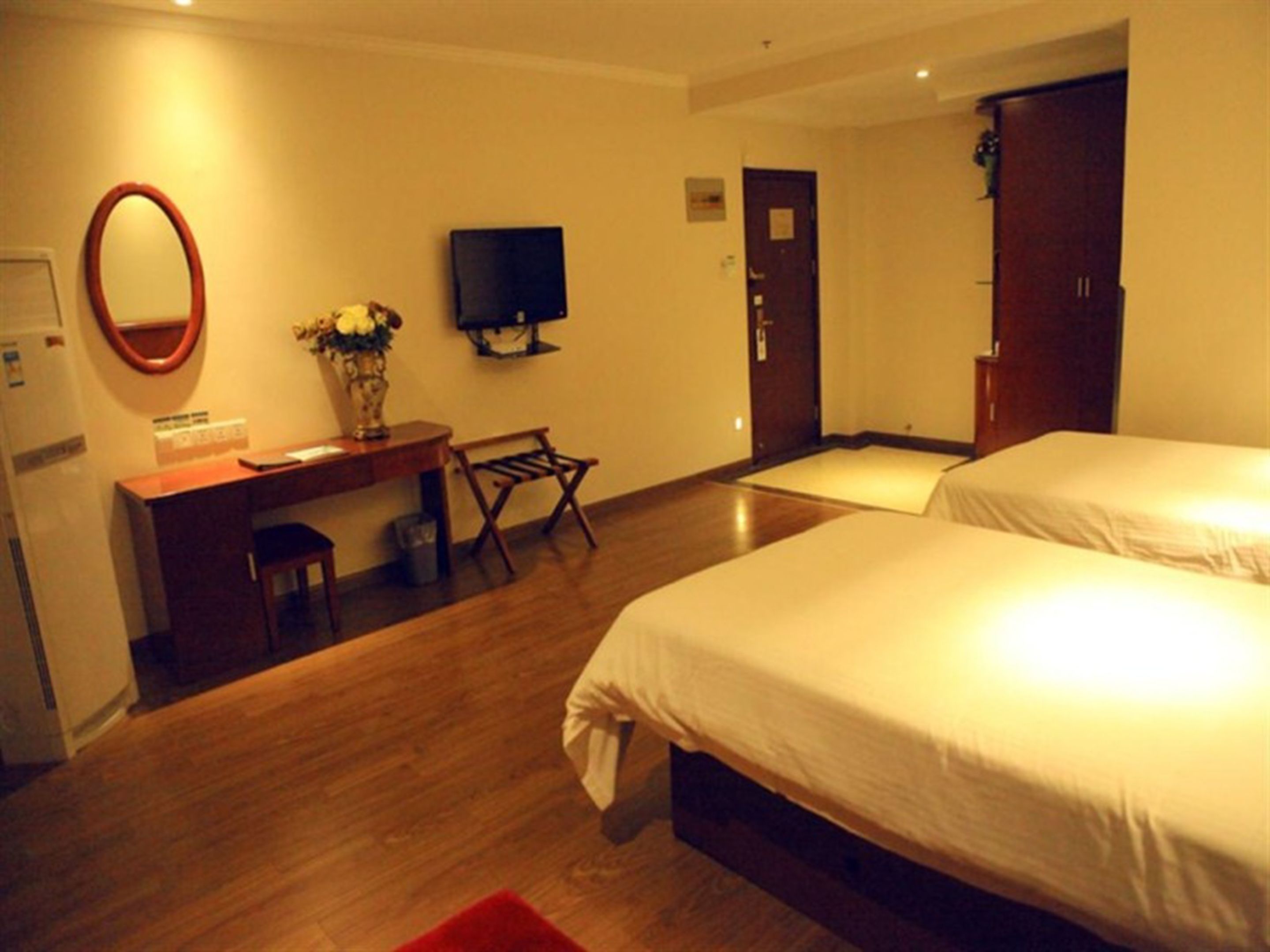 A hotel room with a bed, a desk with a chair, a television, and a wardrobe.