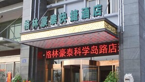 A hotel entrance with a prominent sign, glass doors, and decorative plants.