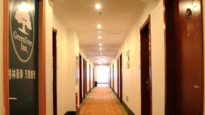 A hotel corridor with doors on both sides, a carpeted floor, and a sign for GreenTree Inn on the left. - GreenTree Inn SuZhou LingBi County Middle JieFang Road Express Hotel (Suzhou)