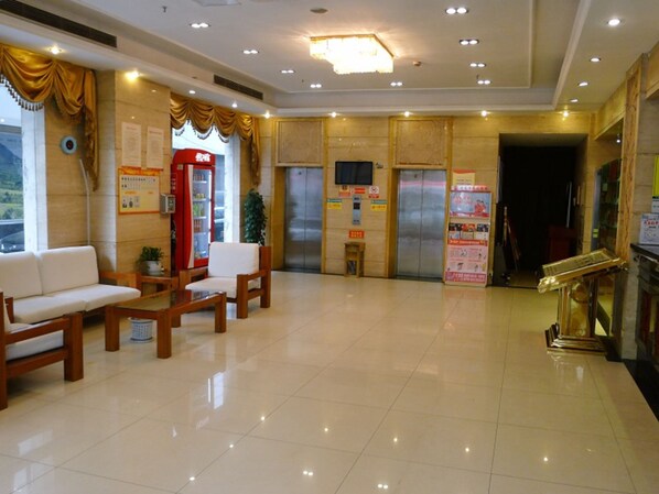 A hotel lobby with a reception desk, seating area, and a vending machine.