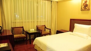 A hotel room with a bed, two chairs, a small table, and a nightstand.