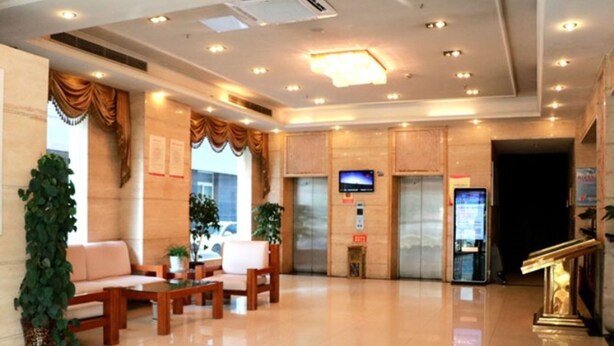 A hotel lobby with a reception desk, seating area, and elevators.