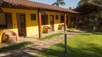 A yellow building with a tiled roof, a covered porch, and a paved walkway.