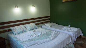 A hotel room with two beds, each with a patterned bedspread and white linens. There are wall-mounted lights above the beds and a painting on the wall.