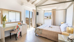 Quarto de hotel moderno com uma cama grande, uma mesa, uma cadeira e uma varanda com vista.