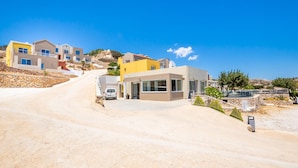 Um bairro residencial com casas modernas, um caminho de entrada pavimentado e um muro de contenção de pedra.