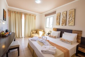 A hotel room with a bed, a desk, a chair, and artwork on the wall. - Nereides (Karpathos)