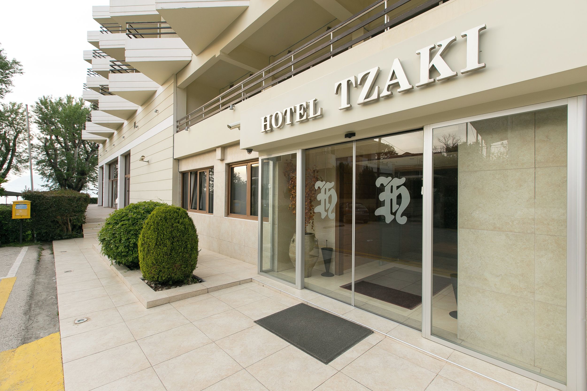 Une façade d’hôtel moderne, ornée d’une enseigne bien visible indiquant « HÔTEL TZAKI ».