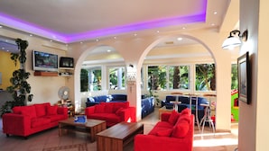 A spacious living area with red sofas, a wooden coffee table, and a TV mounted on the wall. - Hotel Metaxa (Zakynthos)