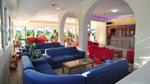 A spacious lobby with blue sofas, red chairs, and a coffee bar. - Hotel Metaxa (Zakynthos)