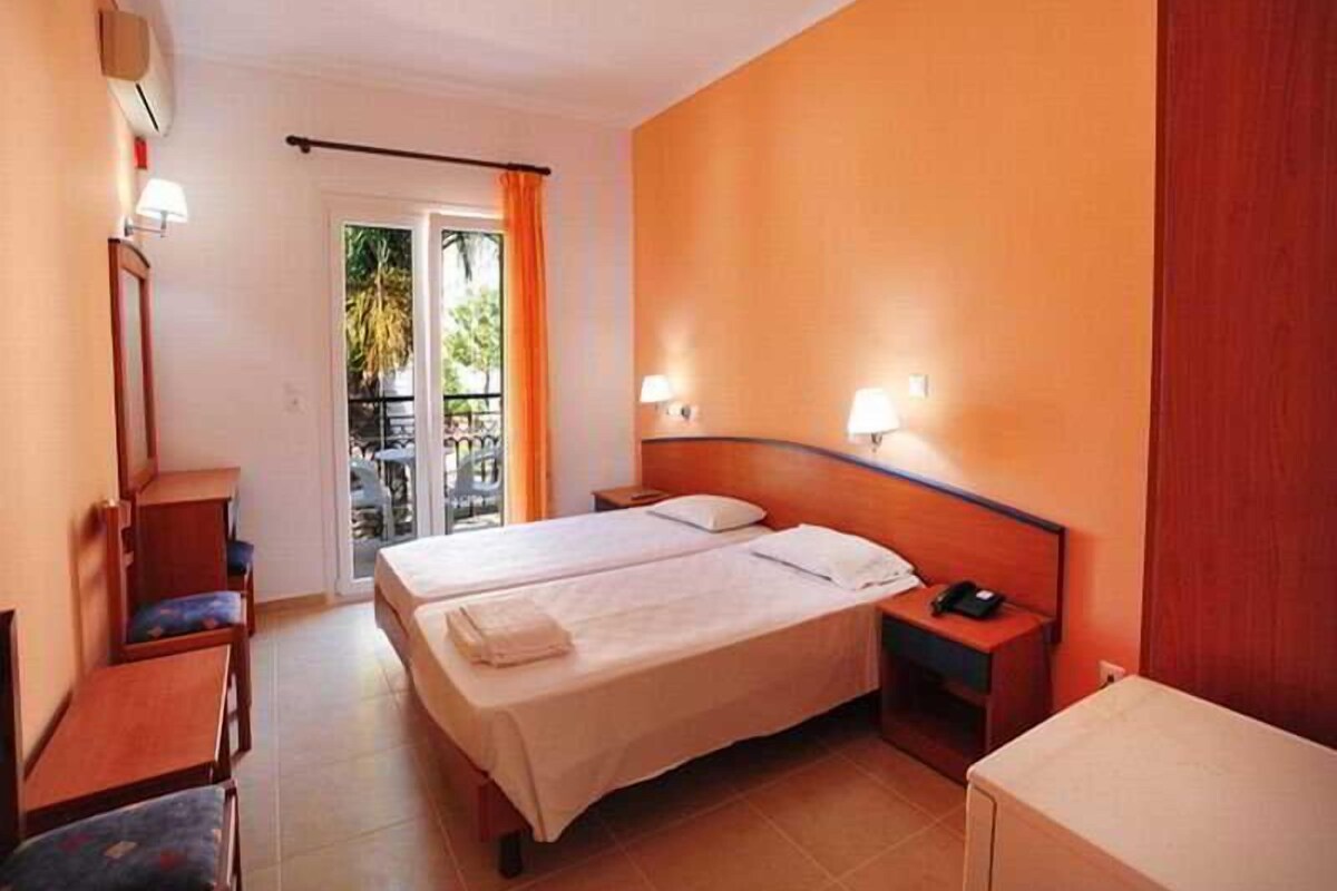 A hotel room with a bed, bedside tables, a desk, and a view of the outdoors.