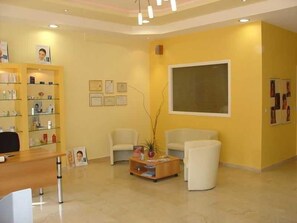 A reception area with a reception desk, two chairs, a coffee table, and a bookshelf. - Oasis (Corfu)