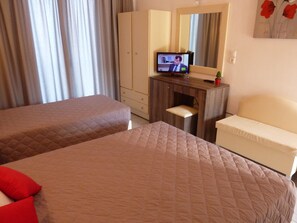Een hotelkamer met twee bedden, een bureau met een televisie, een stoel en een spiegel.