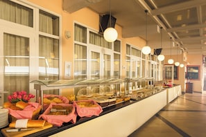 A buffet counter with various food items and baskets, glass display cases, and hanging pendant lights.