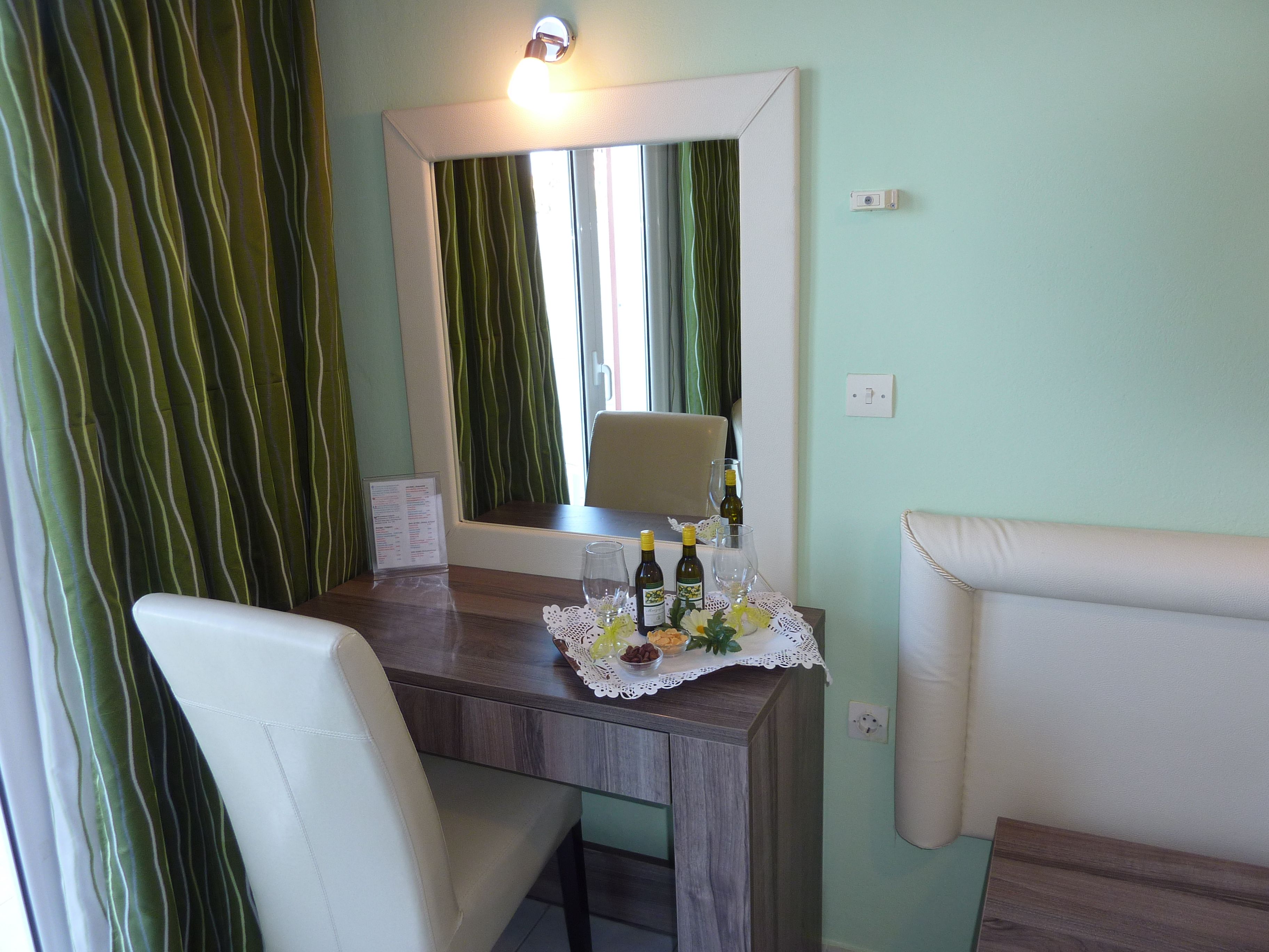 A small dining area with a table, chairs, a mirror, and a window with curtains.
