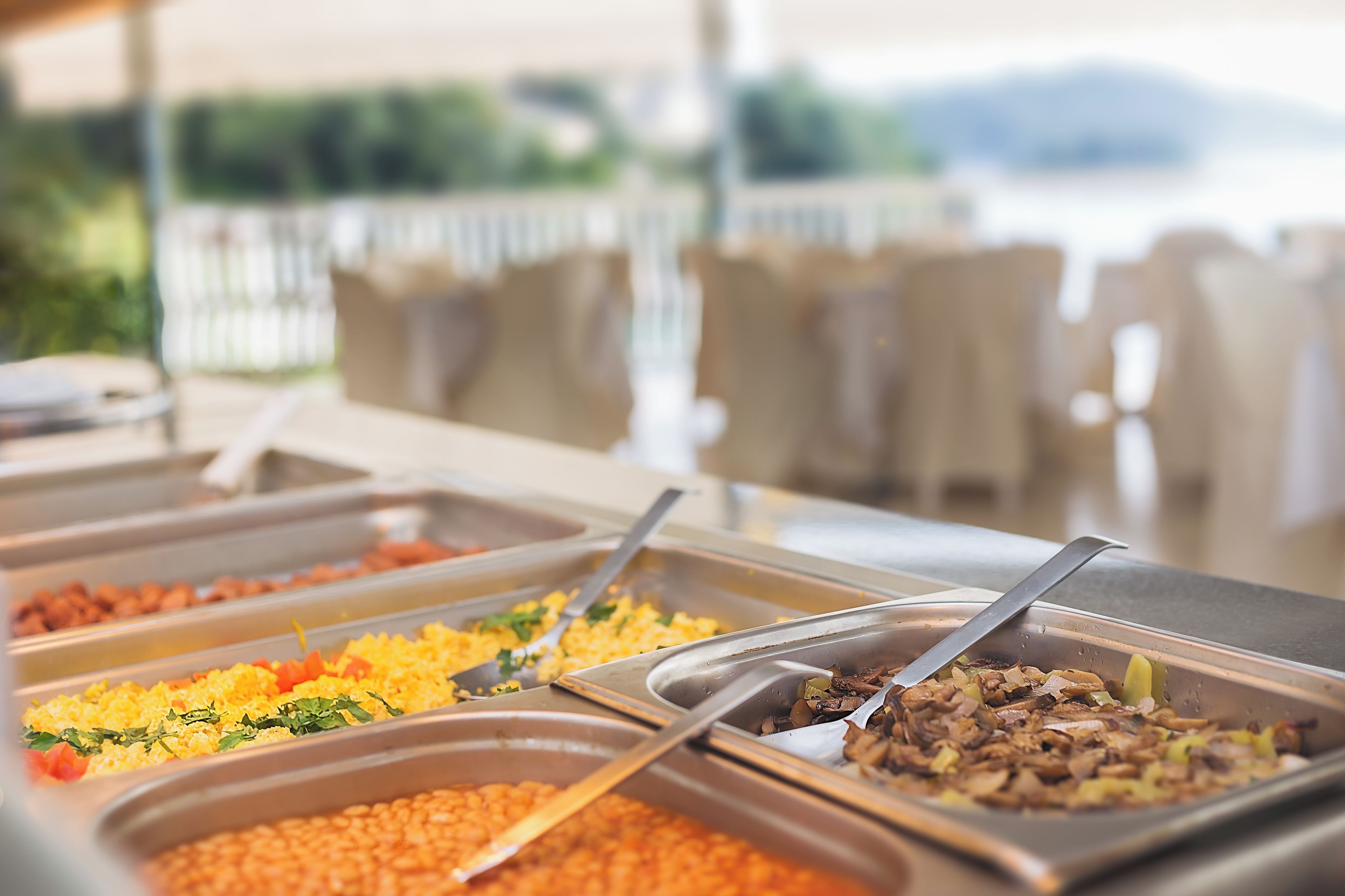 Un bufé con diversas opciones de comida, como arroz, frijoles y vegetales salteados.