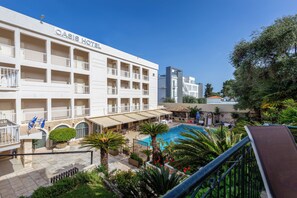 Un hotel con varios balcones, piscina y zonas de estar al aire libre.