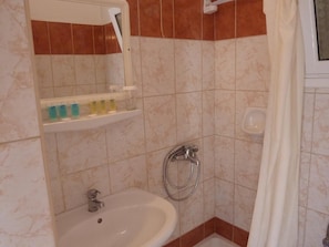 A bathroom with a sink, a mirror, a shower, and a towel rack. - Oasis (Corfu)