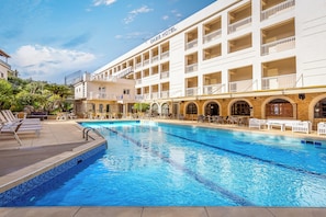 A hotel with a pool, outdoor seating, and multiple balconies.