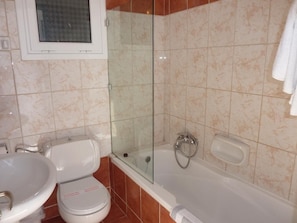 A bathroom with a toilet, sink, and bathtub. - Oasis (Corfu)