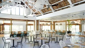 Un restaurante espacioso con techos altos, ventanas amplias y luminarias modernas.