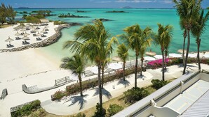 A beach resort with a sandy area, palm trees, and a view of the turquoise sea.