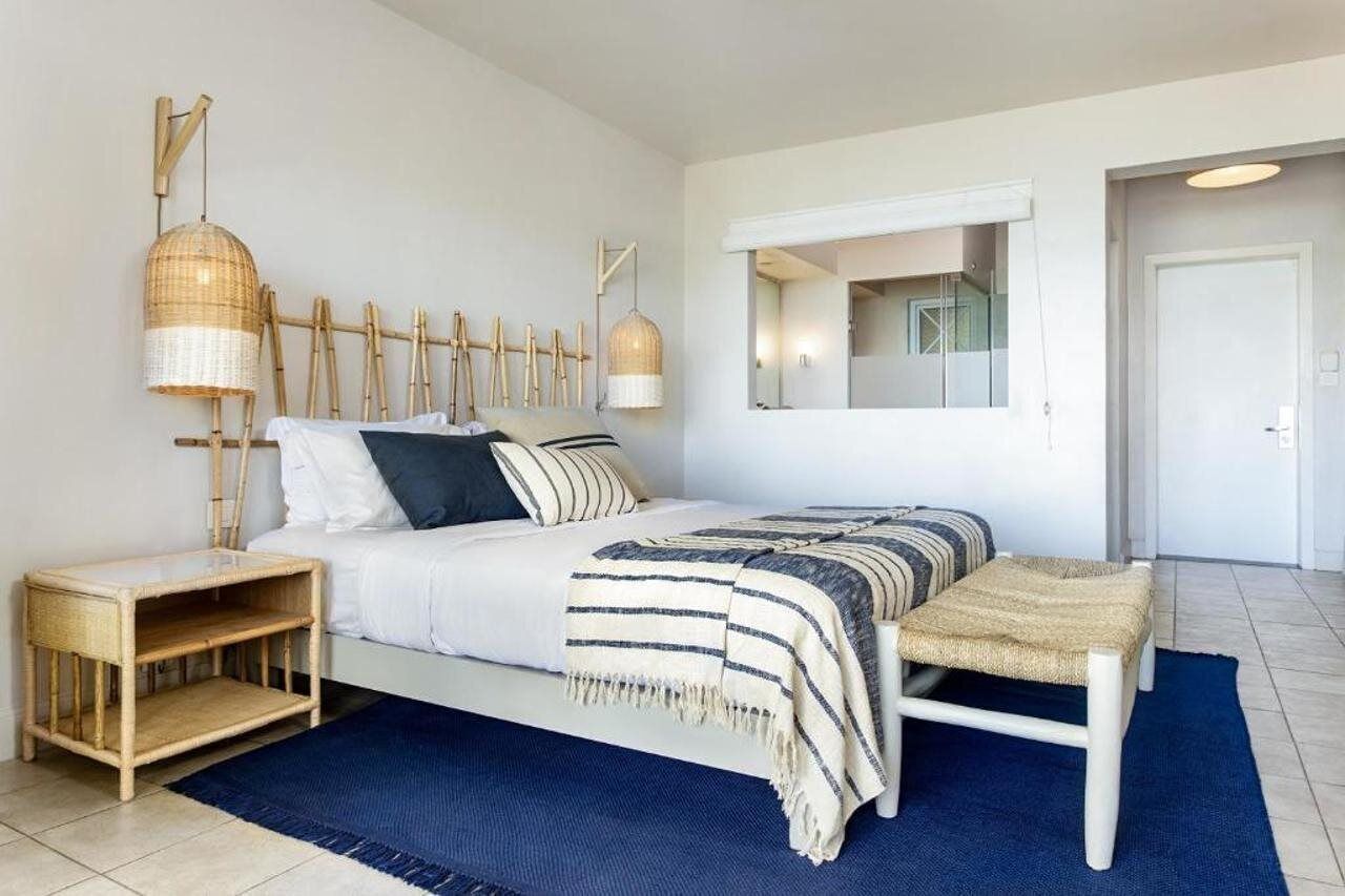 Une chambre à coucher moderne avec un lit, des tables de chevet, un miroir et un luminaire suspendu.