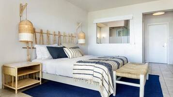 Une chambre à coucher moderne avec un lit, des tables de chevet, un miroir et un luminaire suspendu.