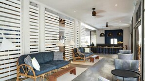 Un interior moderno con un sofá, sillas, una mesita y una zona de bar.